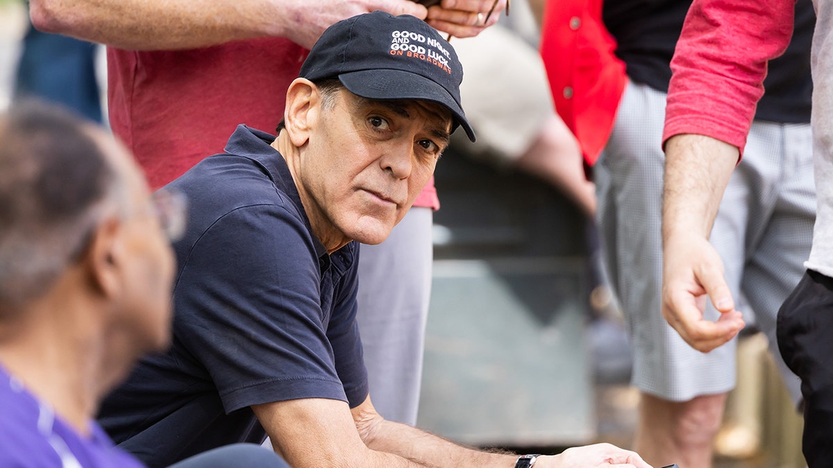 George Clooney wears a blue hat and matching polo shirt