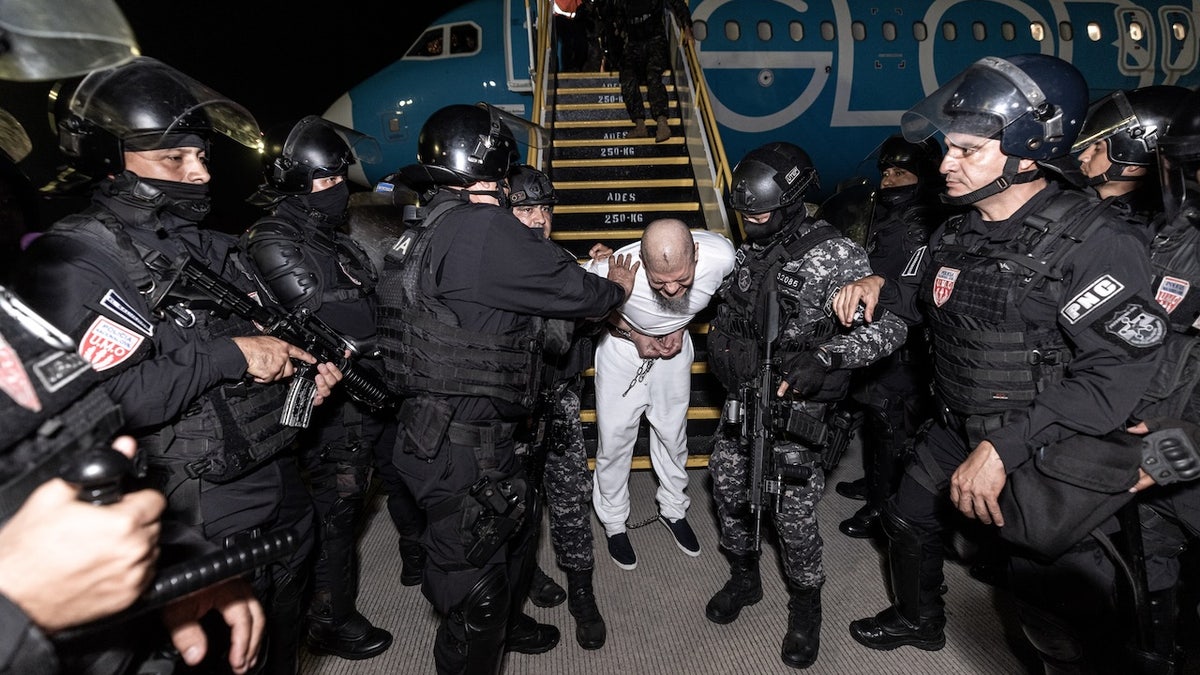 A suspected gang member arrives in El Salvador, where he will be transported to the country's maximum security prison.