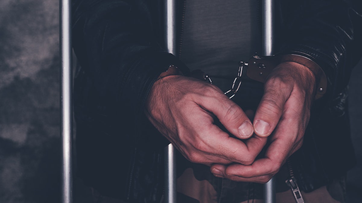 Handcuffed man behind prison bars