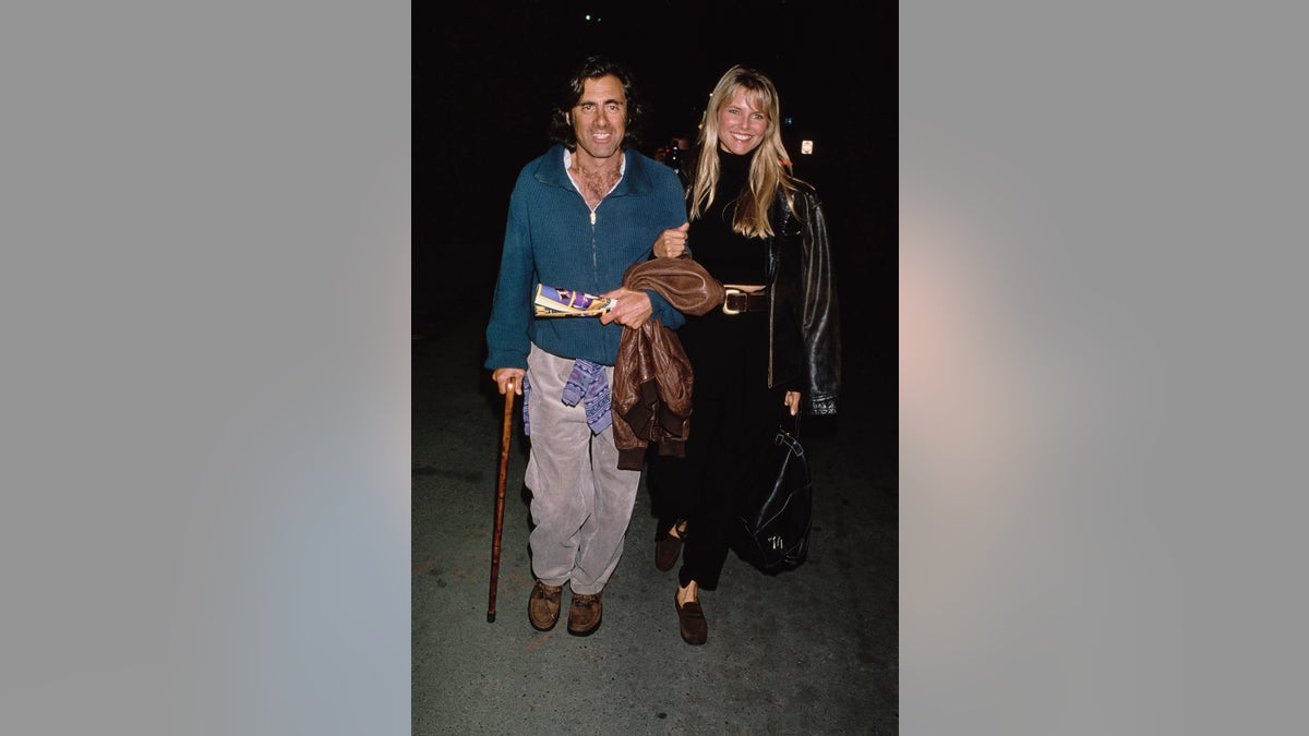 Christie Brinkley with Richard Taubman walking together as he holds a cane.