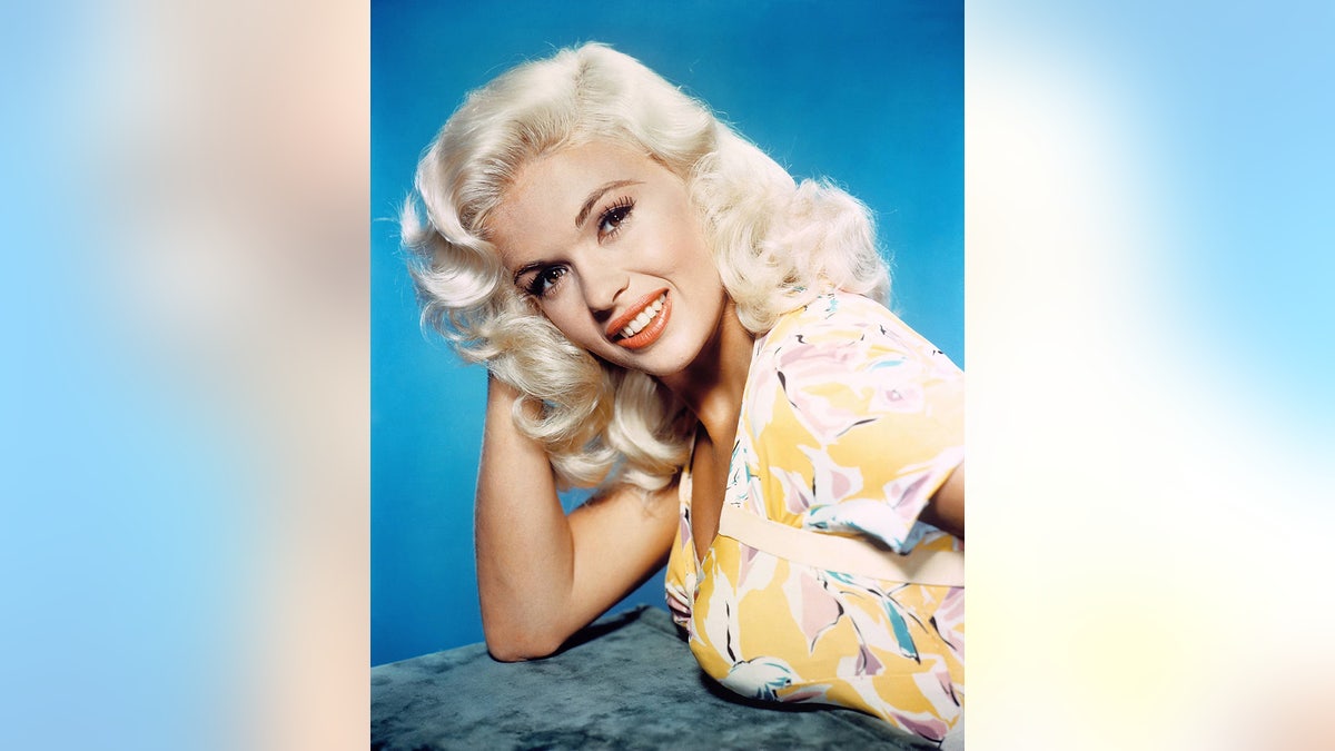 Jayne Mansfield posing in a yellow and white floral dress.
