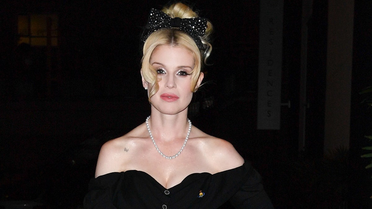Kelly Osbourne wearing an off-the-shoulder black dress with a pearl necklace.