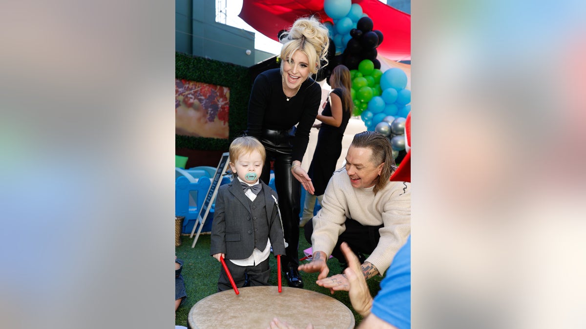 Kelly Osbourne and her partner smiling while watching their son.
