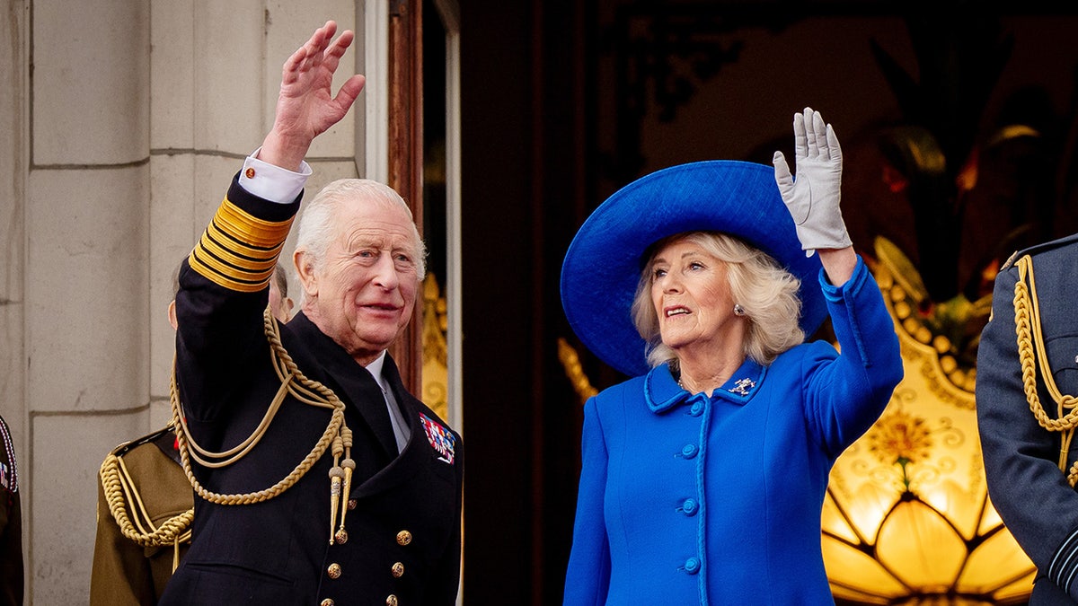 King Charles and Queen Camilla waving to the crowd at Buckingham Palace.