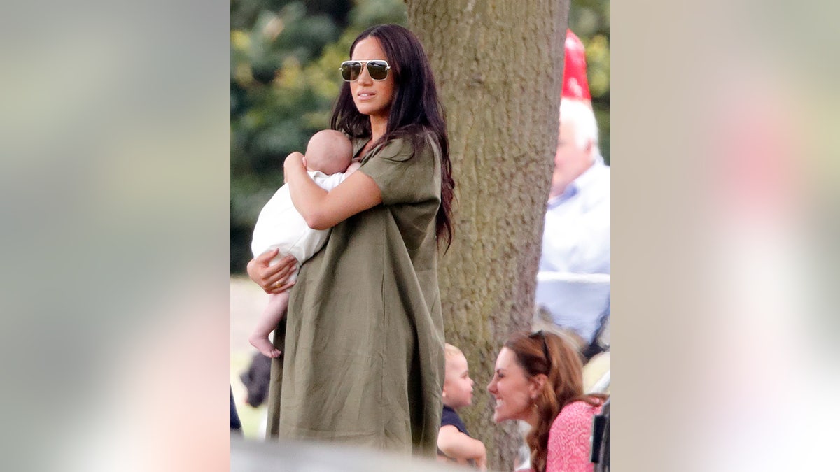 Meghan Markle holding baby Archie as Kate Middleton makes a funny face to Prince George.