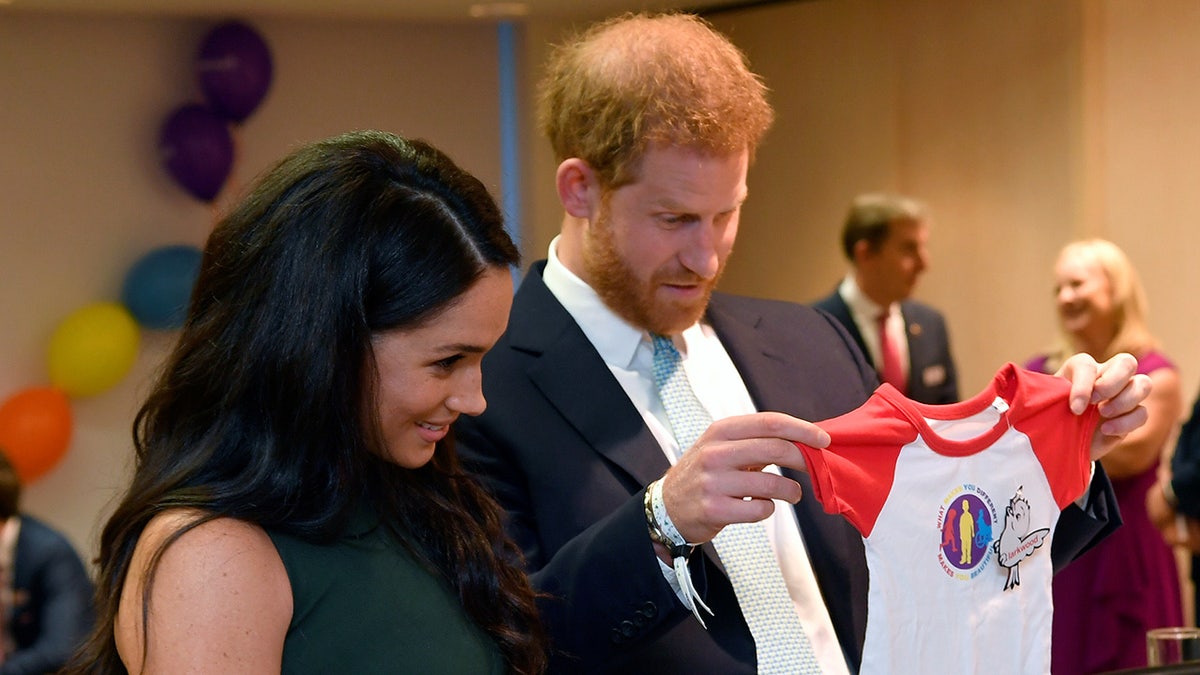 Prince Harry and Meghan Markle looking at baby clothes.