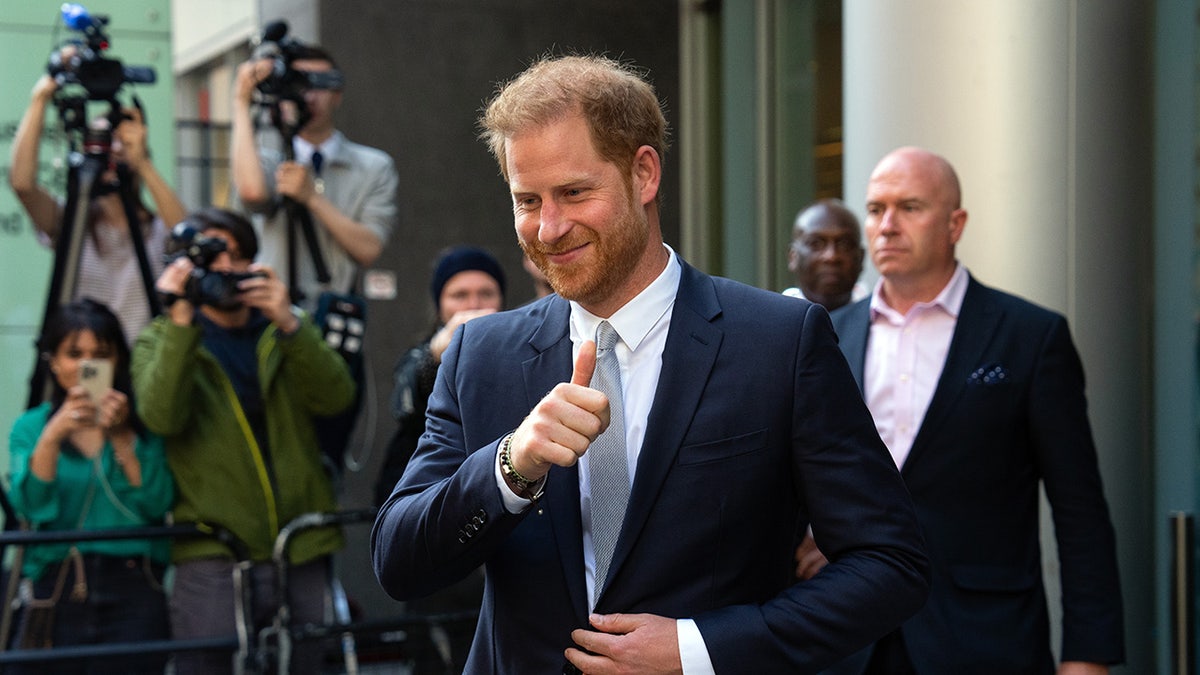 Prince Harry giving a thumbs up in front of the press.