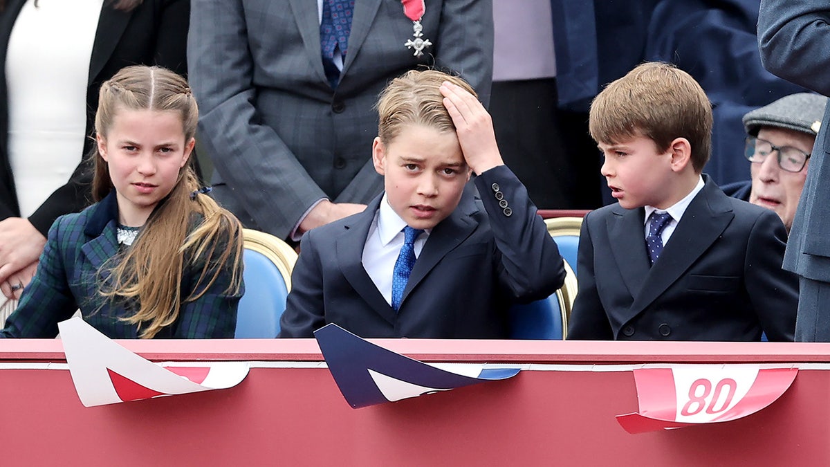 Princess Charlotte, Prince George and Prince Louis sitting together at a crowd in formal wear.