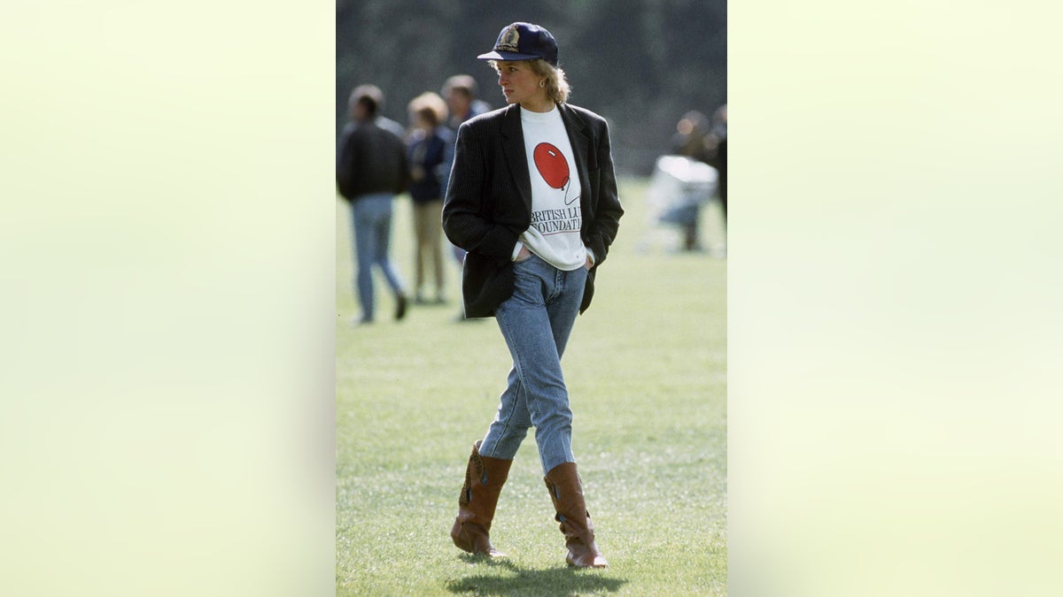 Princess Diana wearing jeans, boots, a loose-fitting white shirt and a dark blue blazer.