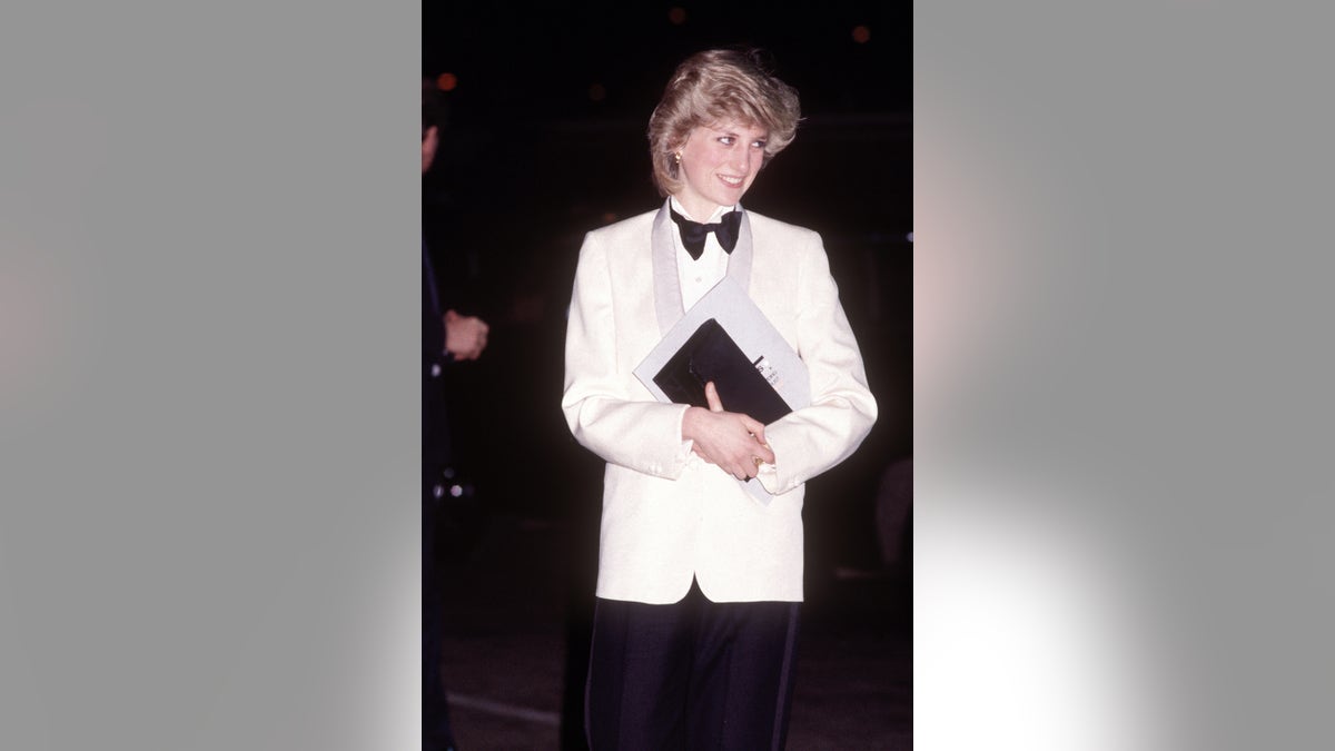 Princess Diana wearing a white tux holding onto a black clutch.