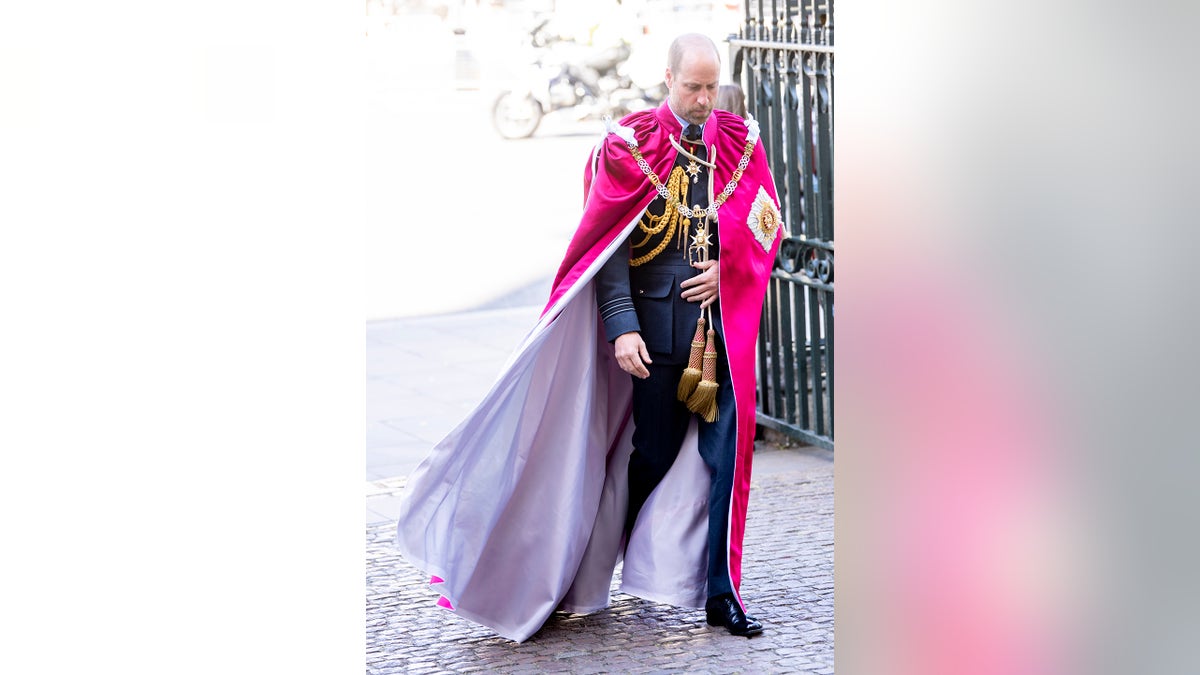 Prince William wearing red robes and walking outdoors.