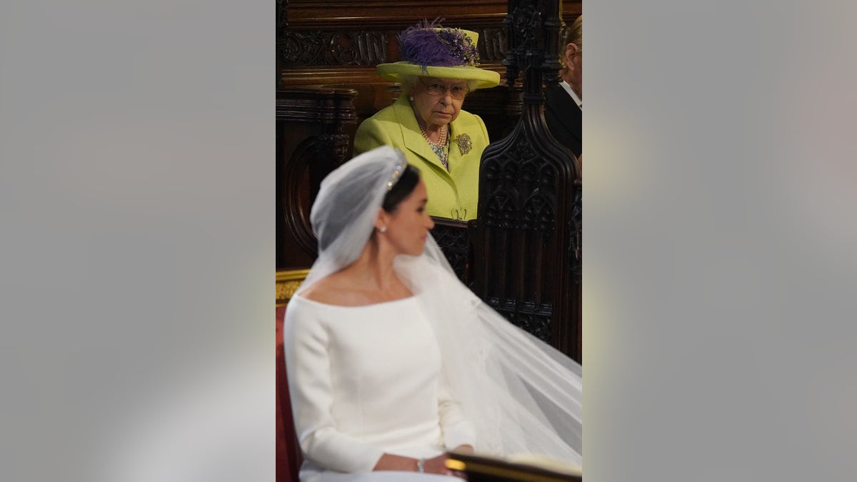 Queen Elizabeth looking at Meghan Markle in her wedding gown.