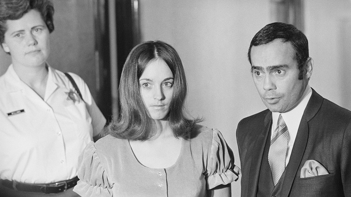Susan Atkins in a dress being held by police.