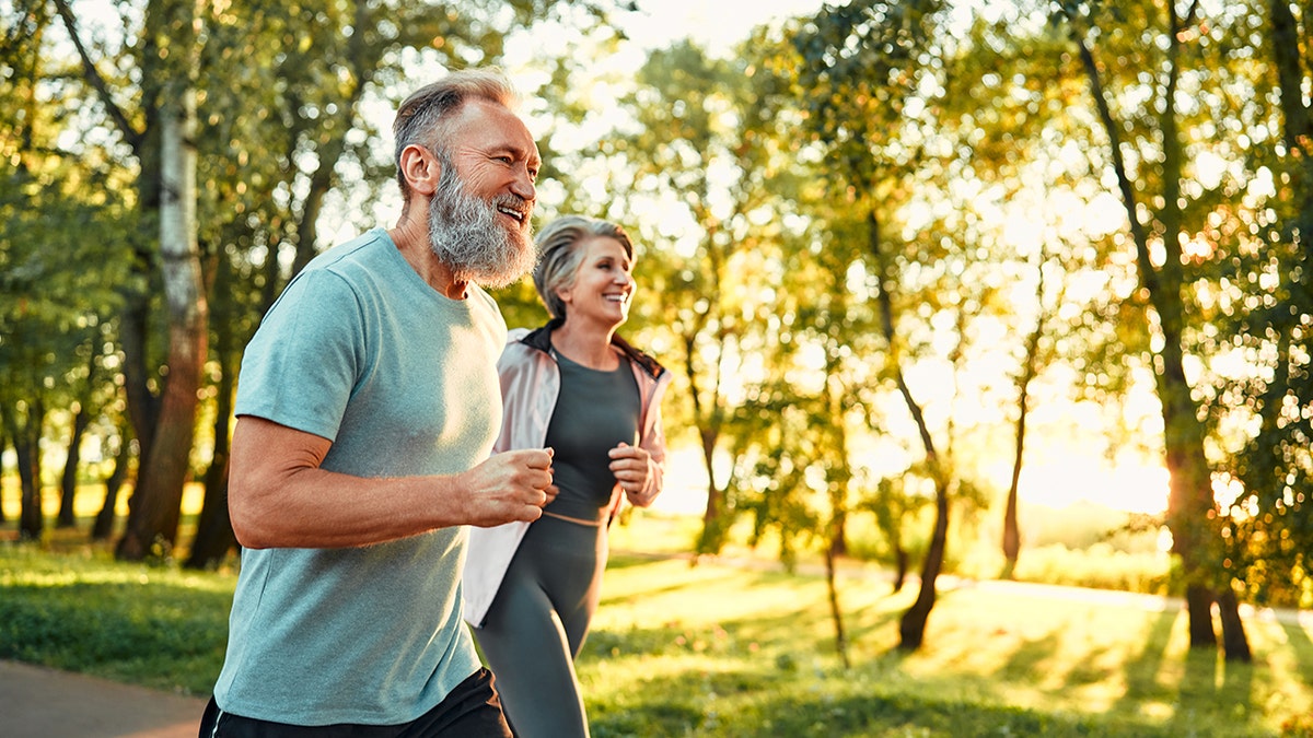 Elderly couple running next to each other outdoors.