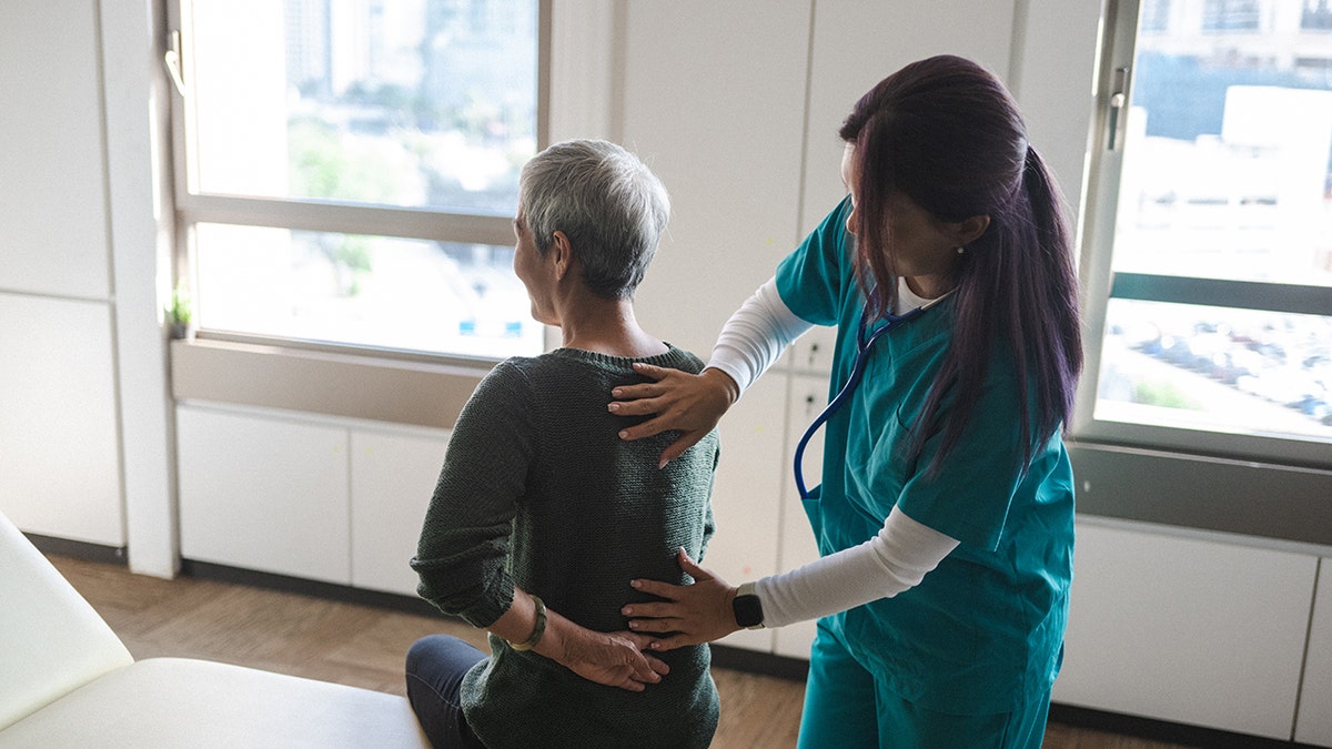 Senior woman suffering from back pain during medical exam.