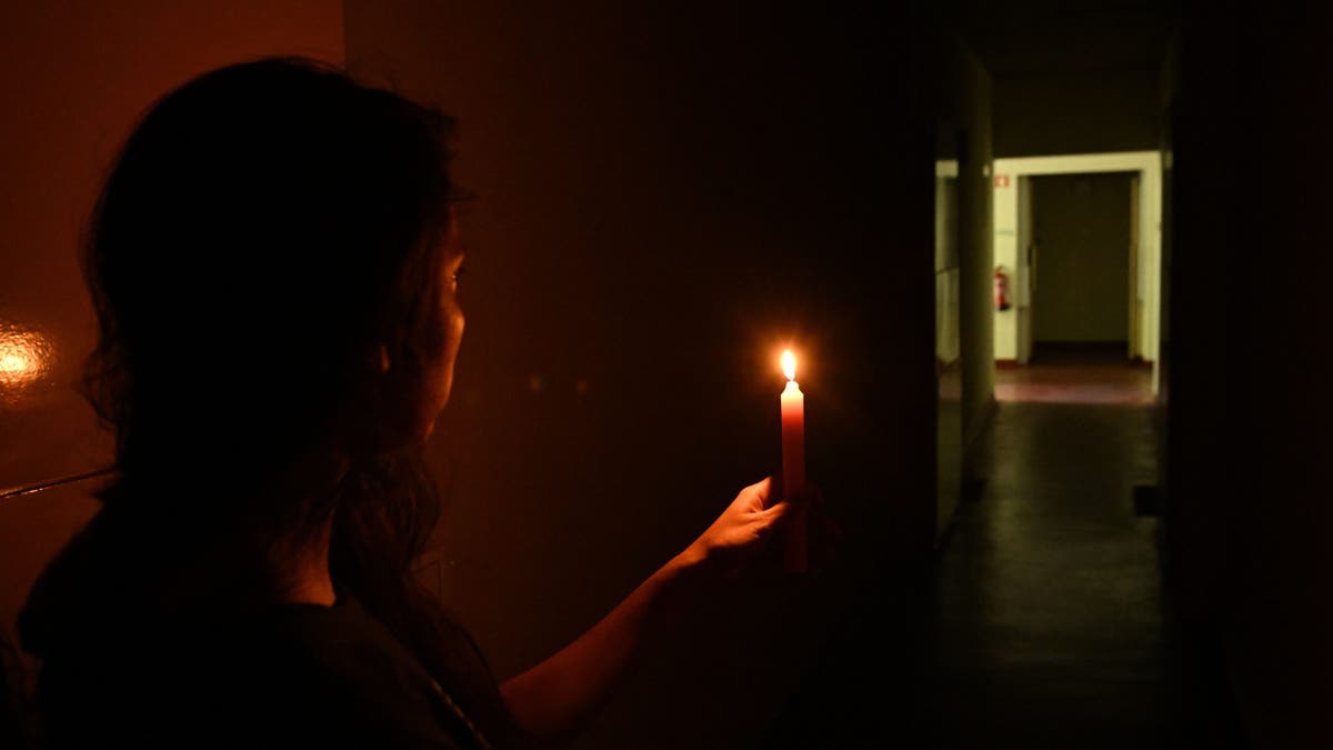 A woman in Lisbon, Portugal, is seen holding a candle for light as Spain, Portugal and other parts of Europe are hit with widespread power blackouts that lasted 10 hours on April 28, 2025. (Stringer/Anadolu via Getty Images)