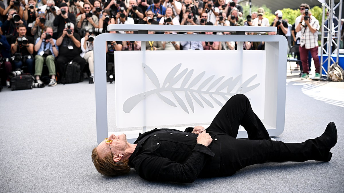 Bono posing on the ground at Cannes 2025