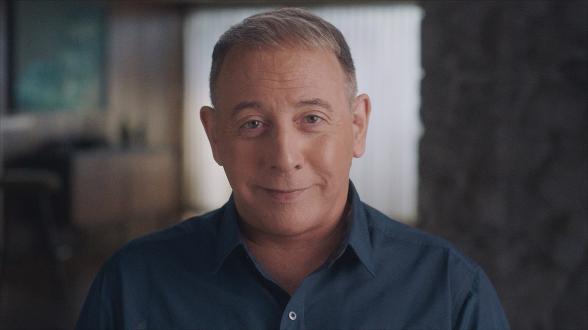 Paul Reubens wearing a dark blue shirt.