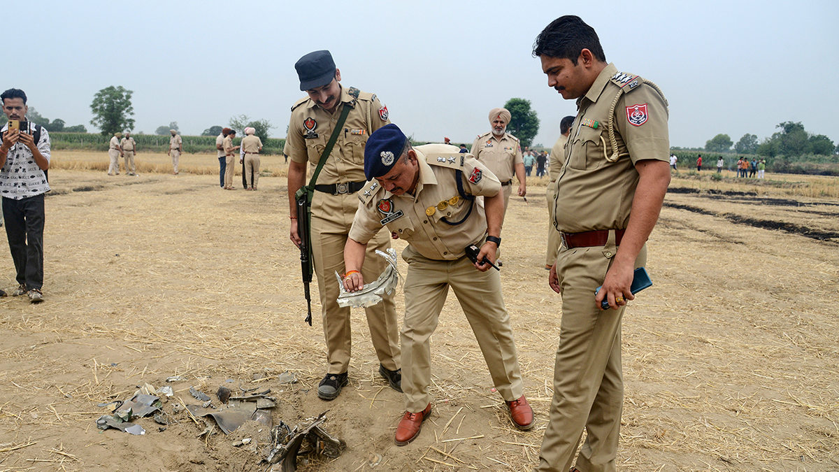 Indian police personnel inspect an object