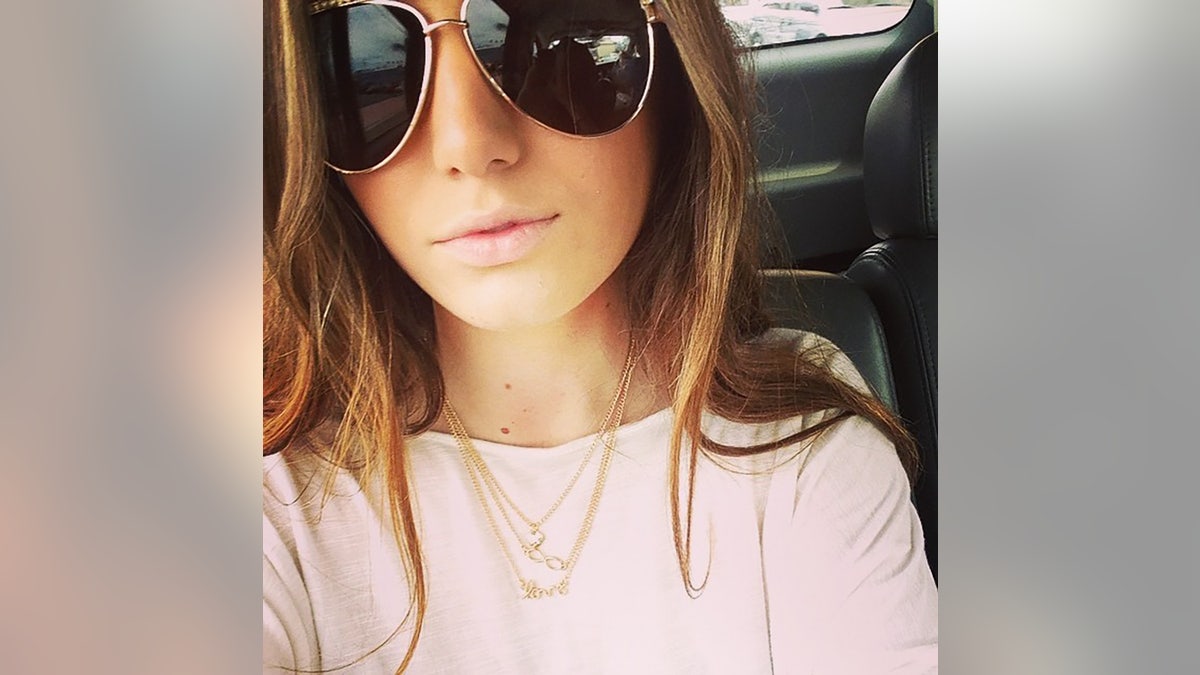 A close-up of Baylee Despot wearing a pinkish sweater and a golden concatenation pinch aviator glasses.