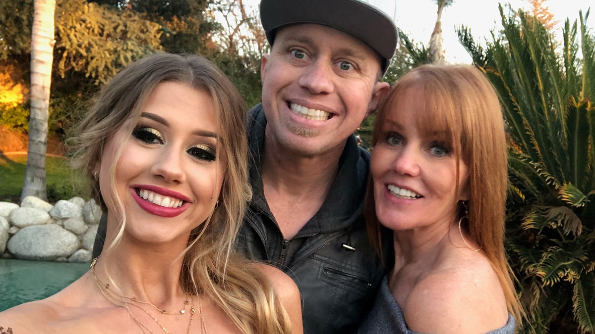 James Kulstad smiling and posing pinch his mother and different woman.