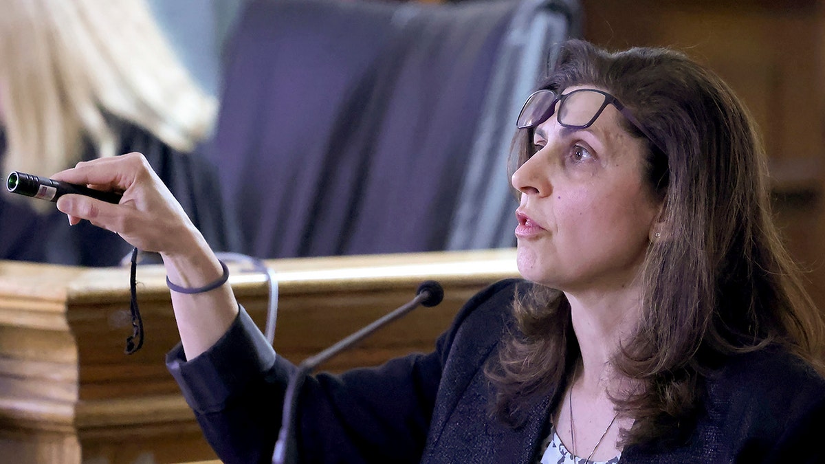 Dr. Irini Scordi-Bello lifted her glasses up to her forehead before pointing at something with a laser during testimony in Karen Read's second trial