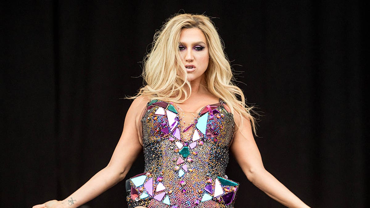 kesha in a sparkly bodysuit against a black background