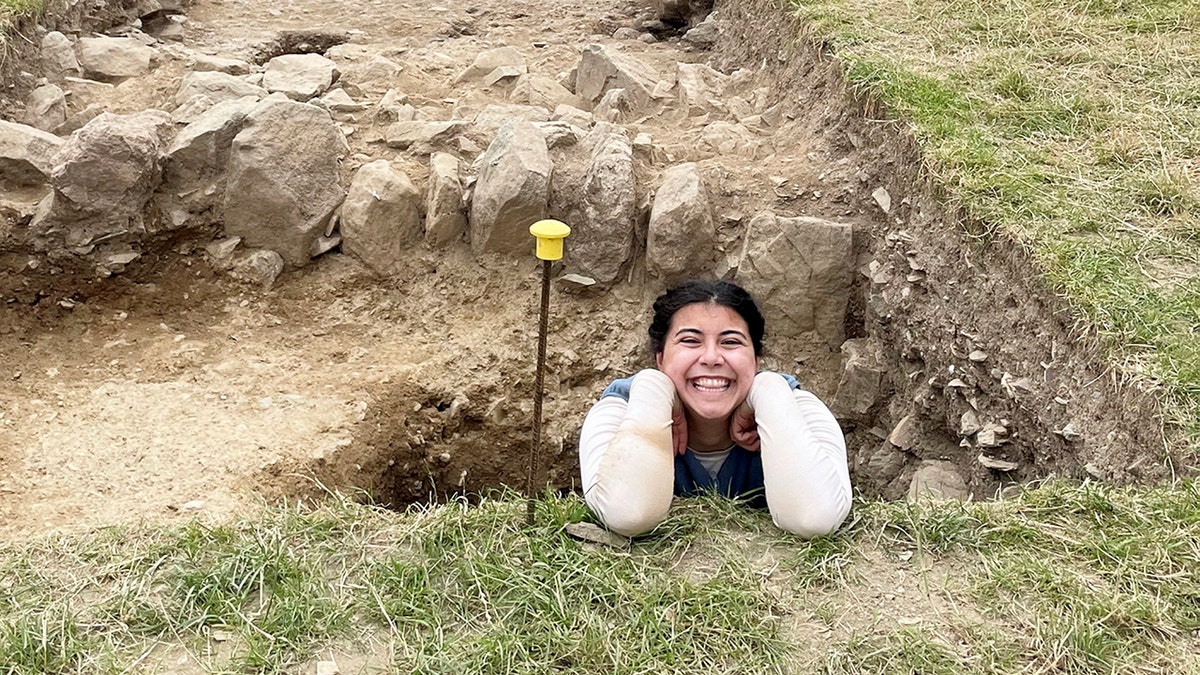 Kyleigh Digiovanni smiles while posing for a photograph in a hole in the ground.