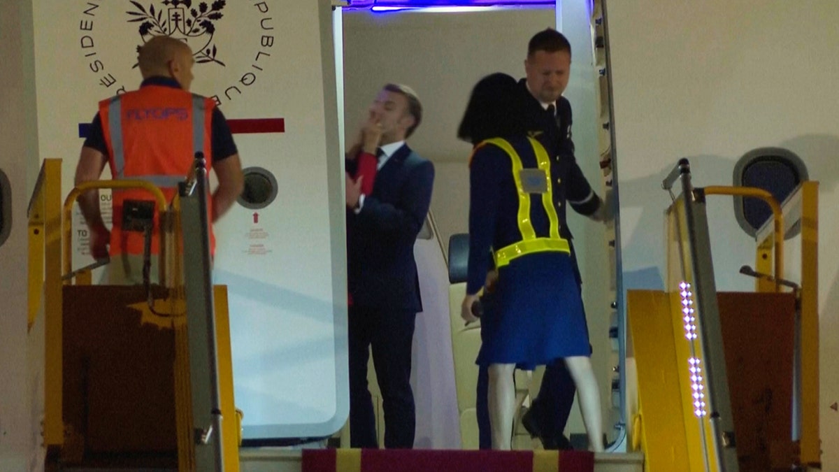 Red sleeved person grabs Macron's face
