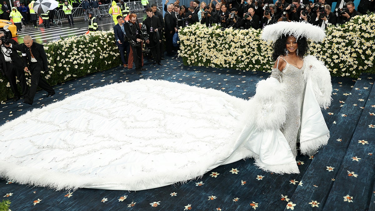 Diana Ross at the met gala in a white dress with a long train.