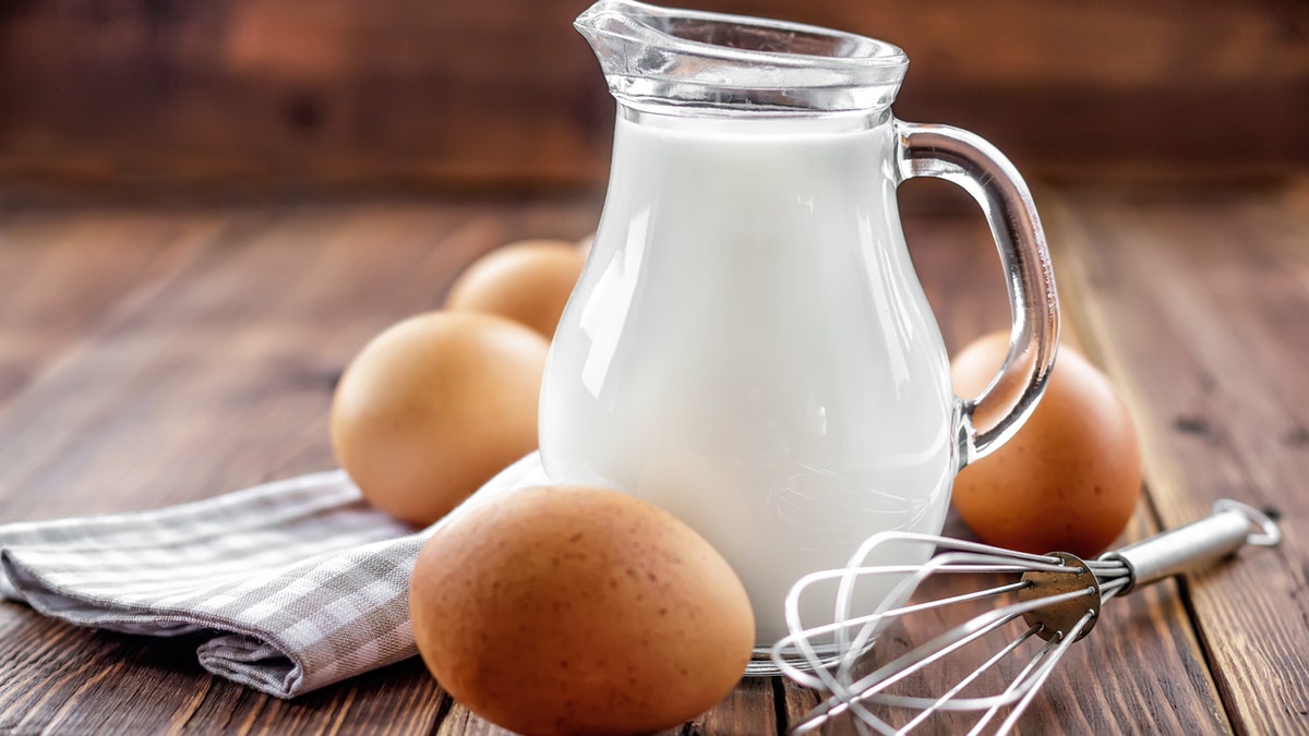 A solid of beverage sits connected a woody array adjacent to a whisk, immoderate eggs and a napkin.