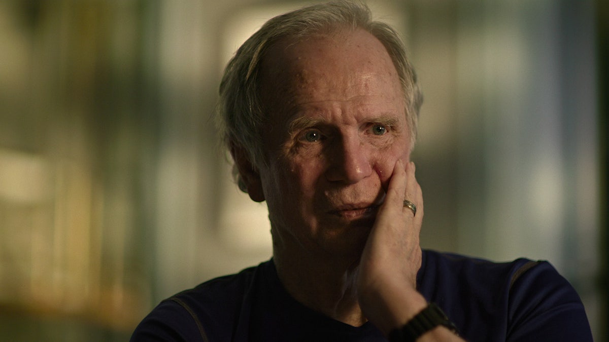 A close-up of James Lewis touching his face.