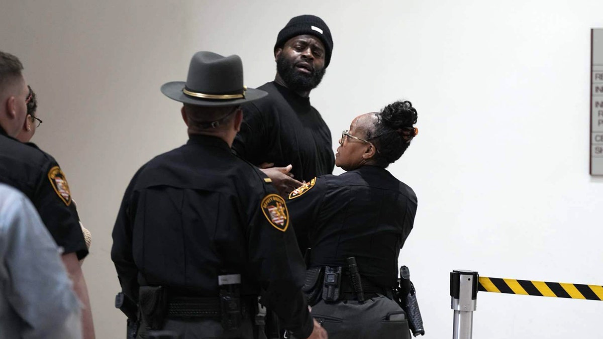 A man is led out of court after a disturbance during Rodney Hinton, Jr.'s court appearance for the alleged killing of an Ohio Sheriff's deputy
