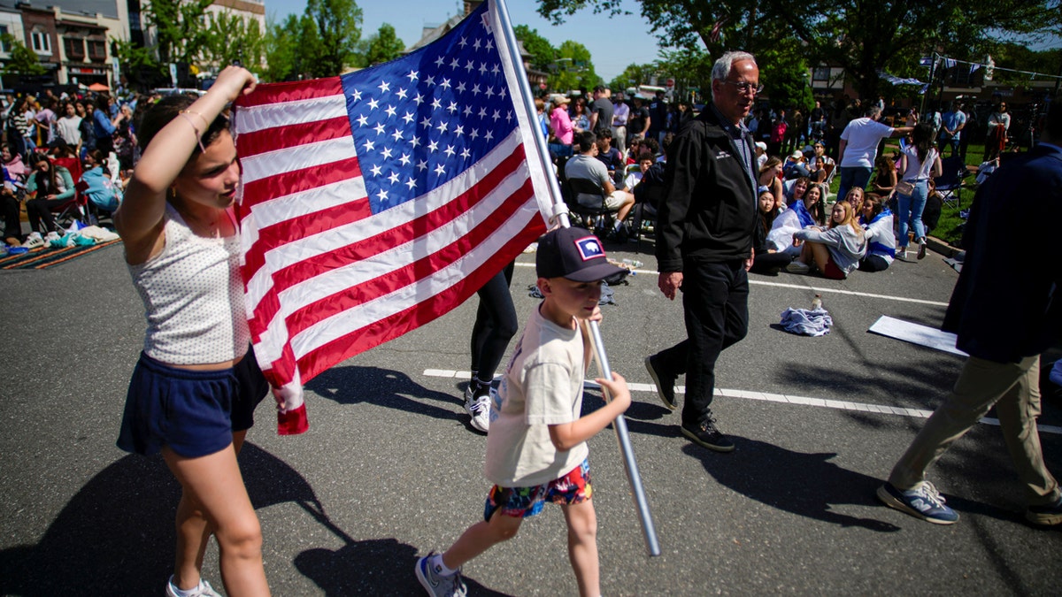A young boy holds up a large American flag following the release of Israeli-American hostage Edan Alexander from captivity by Hamas in Gaza.