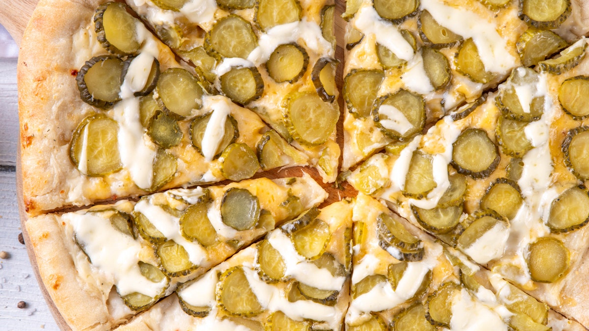 A closeup view from above of a pickle pizza.