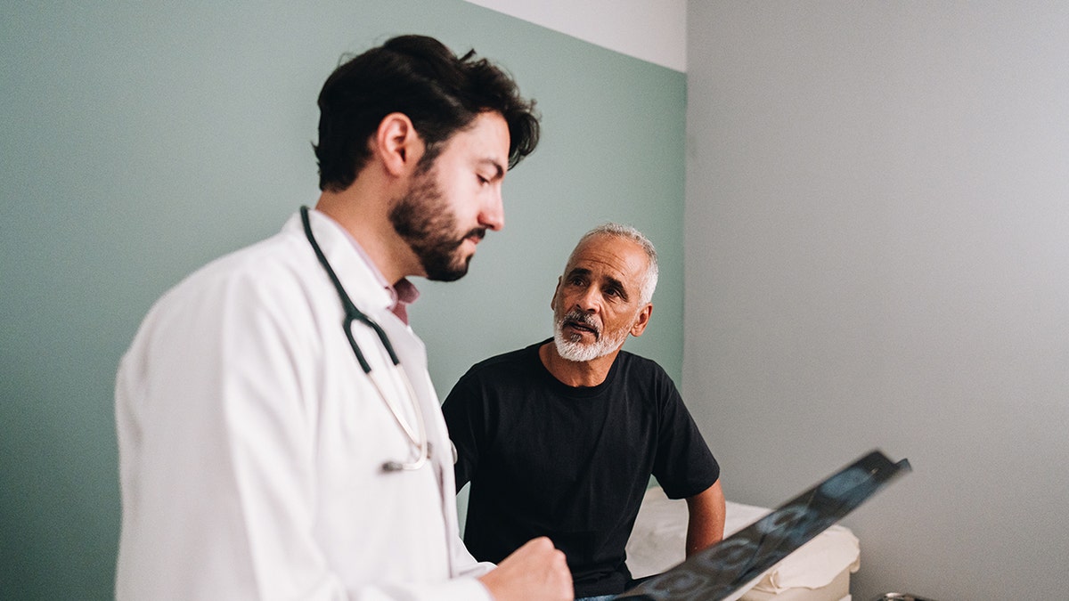 Doctor talking with his patient while show a x-ray image on a doctor's office. To be used in piece about prostate cancer screenings