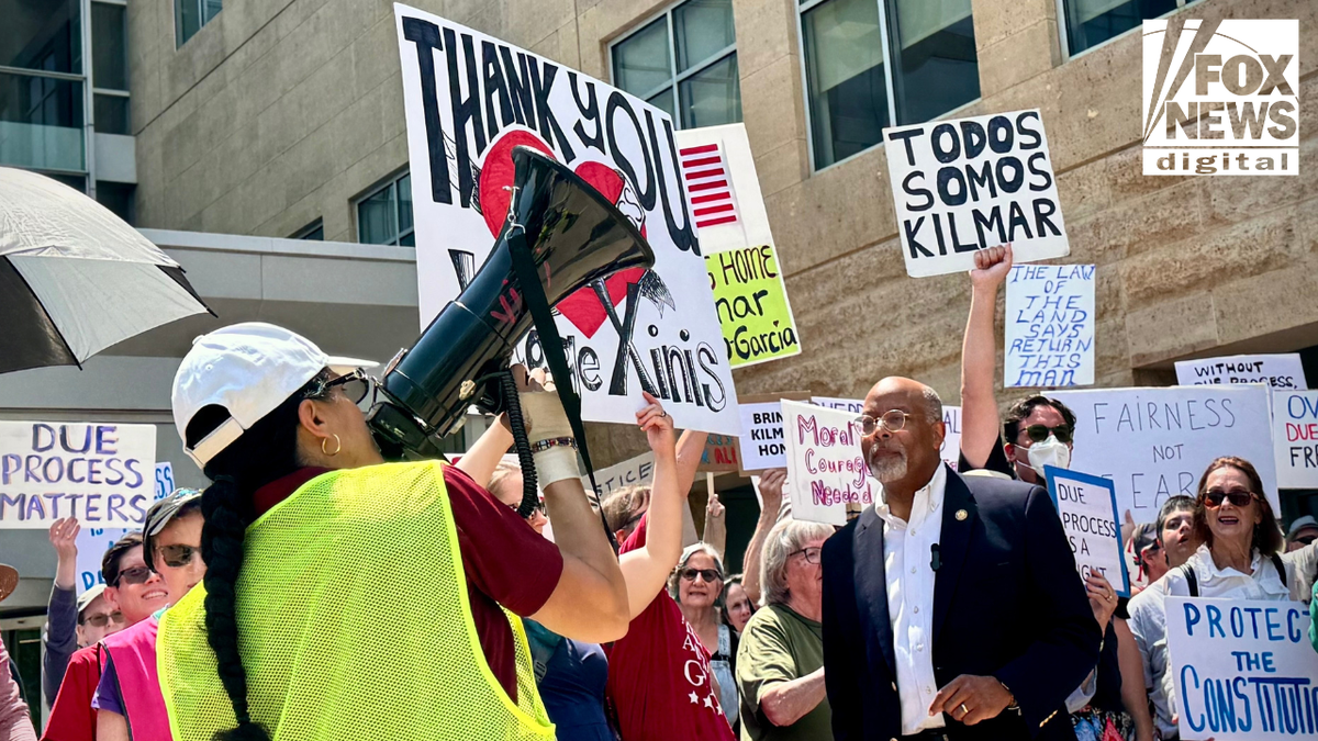 A woman speaks through a megaphone at a rally outside the U.S. District Court in Greenbelt, Maryland, where demonstrators hold signs supporting Kilmar Abrego Garcia and praising Judge Paula Xinis.