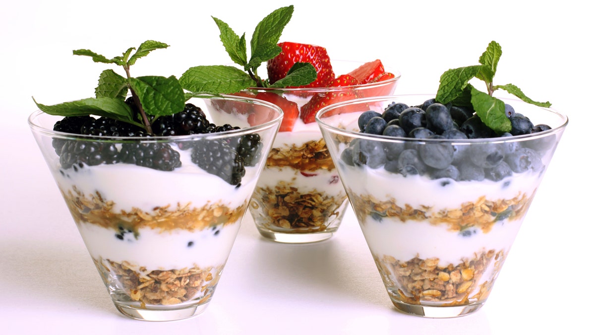 A raspberry, strawberry and blueberry parfait are arranged on a white background.