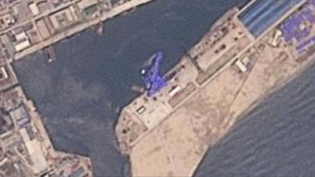 satellite shows the destroyer covered in a blue tarp