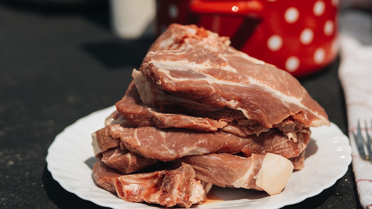 A pile of steak is on a white plate on a table.
