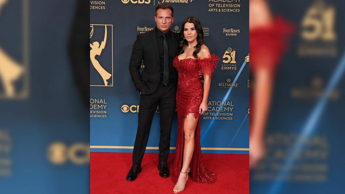 Steve Burton wears black suit with Michelle Lundstrom in red dress.