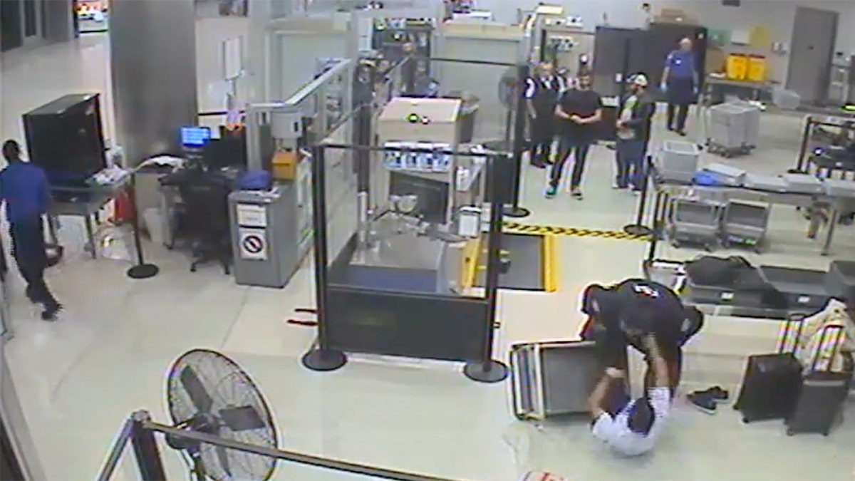 Video still of TSA officers pinning Cameron McDougall to the floor near a security checkpoint at Miami International Airport