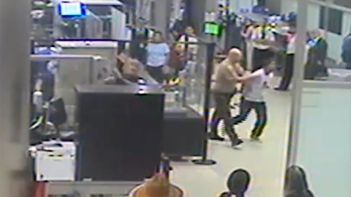 Cameron McDougall being escorted by authorities through the security checkpoint at Miami International Airport