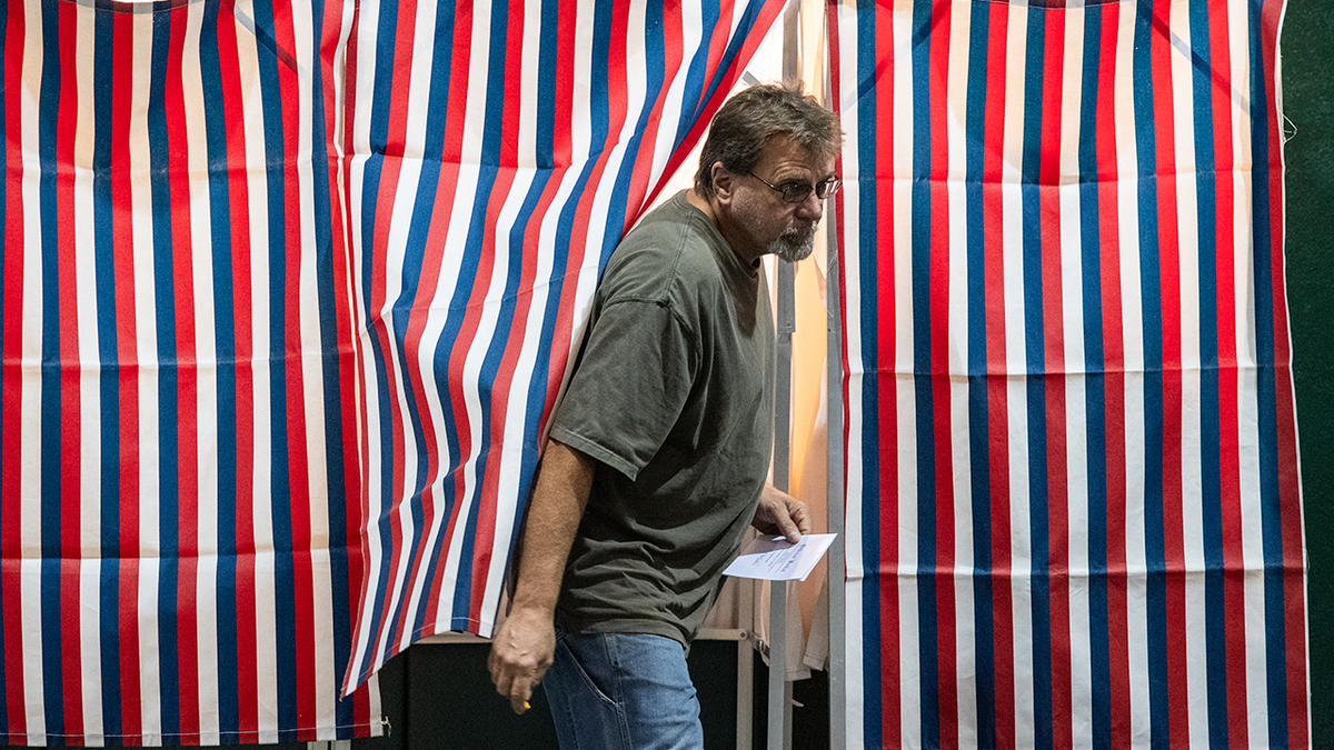 A man exits a voting booth.