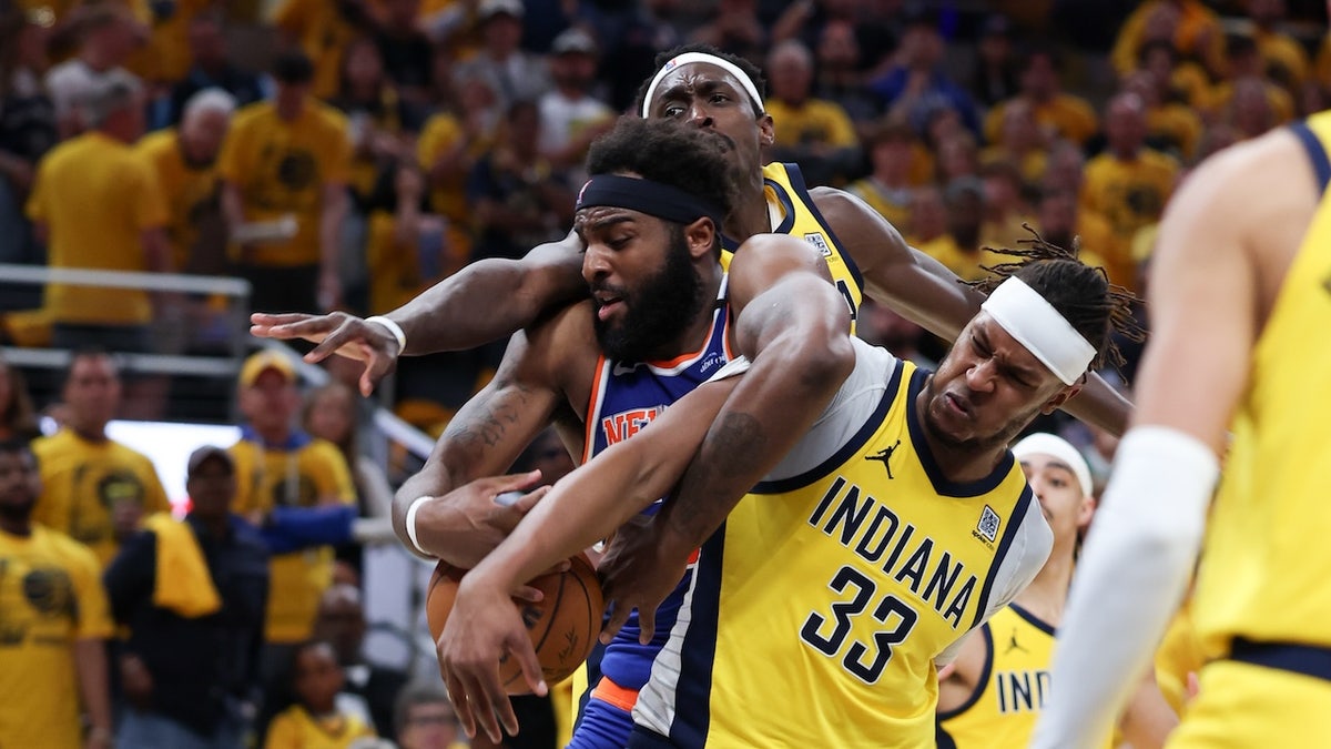 Pusat New York Nix Mitchell Robinson (23) memakai pertempuran sepak bola melawan Indiana Pesrez Pascal Siamie (43) dan Central Miles Turner (33 tahun) pada kuarter ketiga selama pertandingan keenam Wilayah Timur di kualifikasi di Liga Profesional Amerika 2025 di Genbridge Midal.