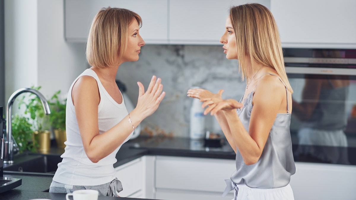 Two blonde women argue in a kitchen.