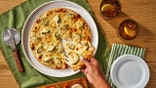 A hand pulls off a slice of California Pizza Kitchen's dill pickle pizza, as seen from above.