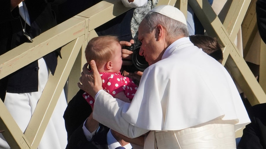 Pope Leo XIV holds a baby ahead of his inaugural mass.