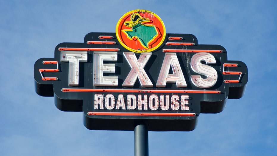 Texas Roadhouse Sign appears in front of a blue sky.