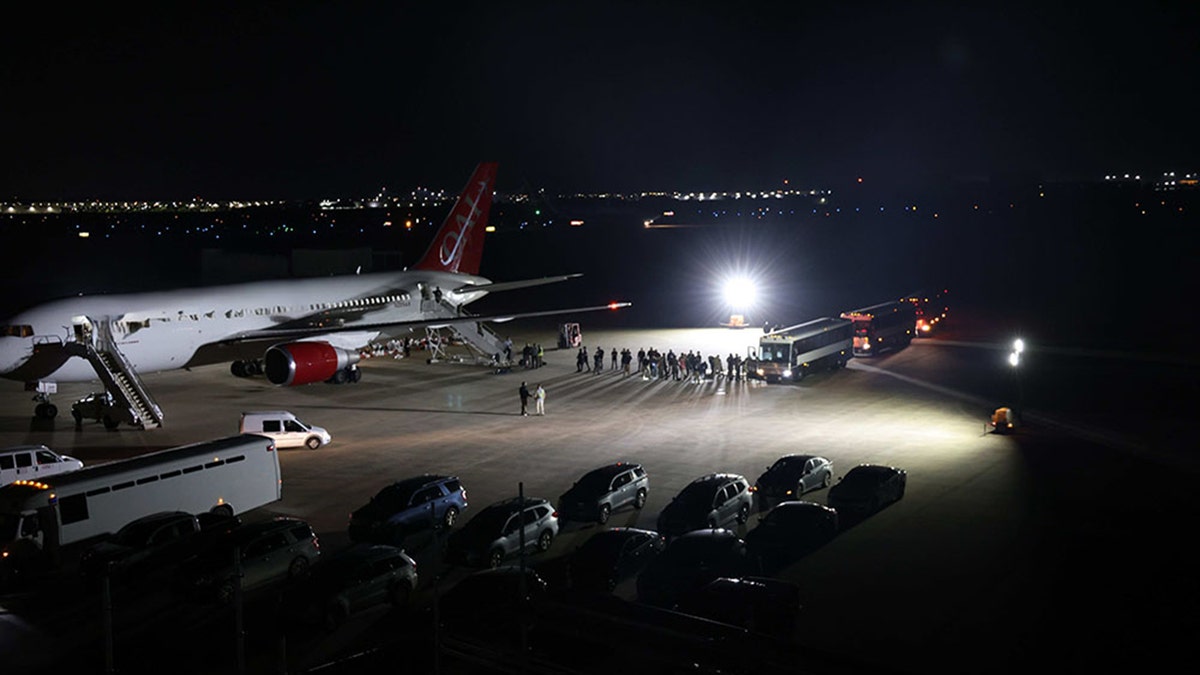 Night view of ice deportation operation with a large passenger plane and icy vehicles